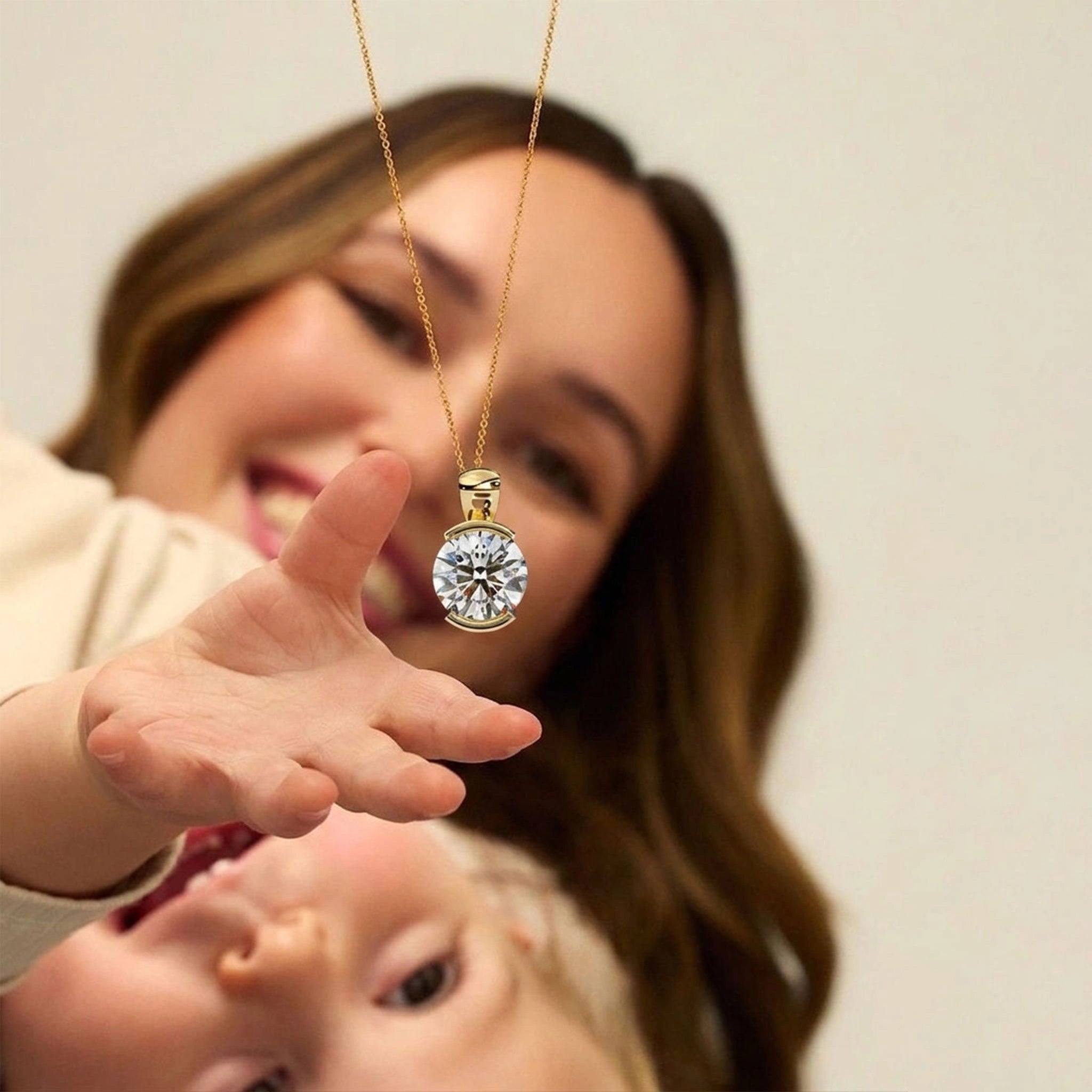 Happy mom holding lab grown diamond pendant necklace in yellow gold chain as best Mother's Day gift.